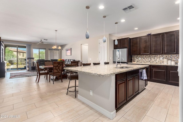 kitchen featuring pendant lighting, sink, a kitchen island with sink, appliances with stainless steel finishes, and a breakfast bar area