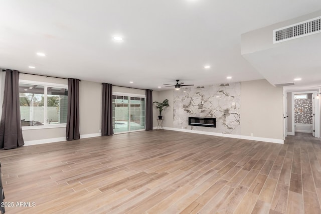 unfurnished living room with plenty of natural light, light wood-type flooring, a fireplace, and visible vents