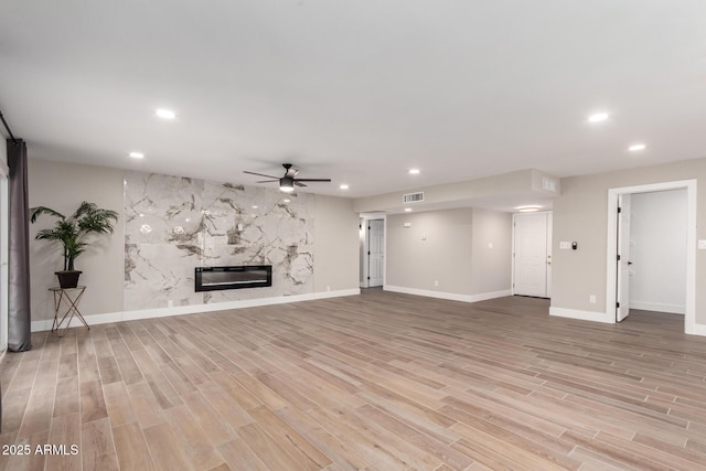 unfurnished living room featuring light wood finished floors, a premium fireplace, visible vents, and recessed lighting