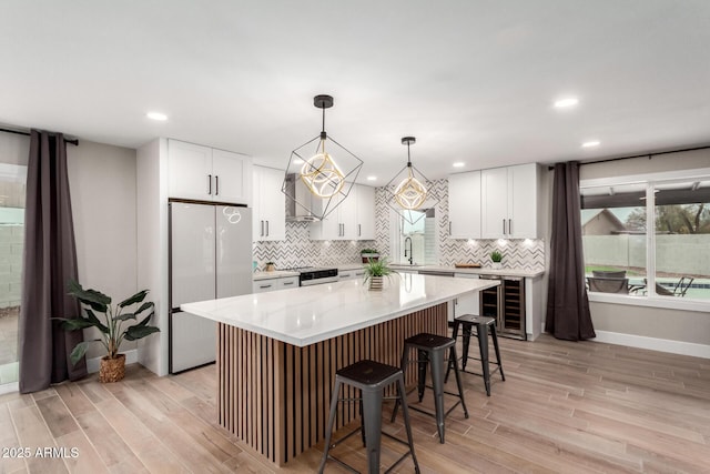 kitchen featuring wine cooler, backsplash, freestanding refrigerator, and light wood-style floors