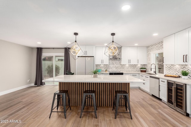 kitchen with beverage cooler, a sink, stainless steel dishwasher, fridge, and a center island