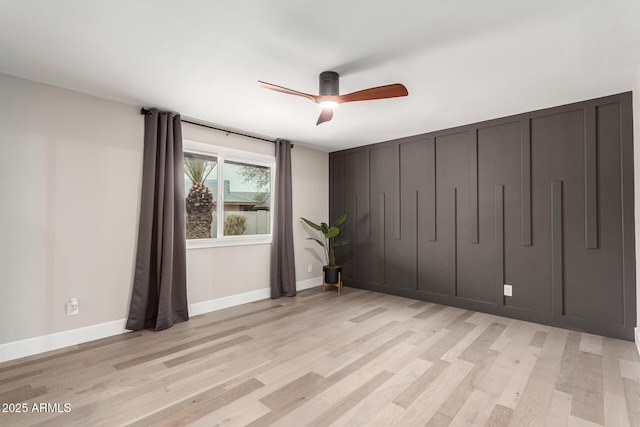 unfurnished room with baseboards, a ceiling fan, and light wood-style floors