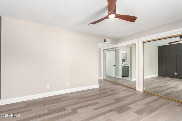 unfurnished bedroom featuring two closets, visible vents, light wood-style flooring, ceiling fan, and baseboards