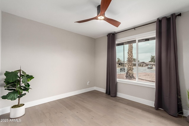 empty room with ceiling fan, baseboards, and wood finished floors