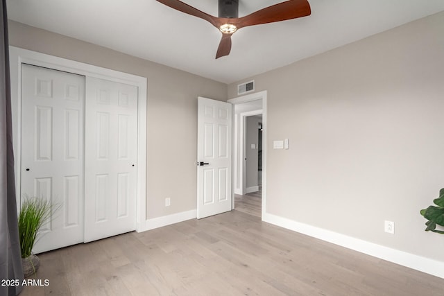 unfurnished bedroom featuring visible vents, baseboards, a ceiling fan, light wood-style flooring, and a closet