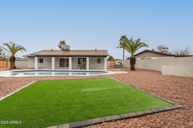 rear view of property with a patio area, a fenced backyard, a fenced in pool, and a yard