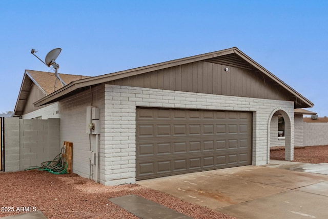 garage featuring driveway and fence