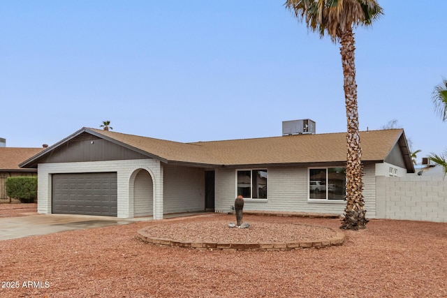 ranch-style home with central AC unit, a garage, brick siding, fence, and concrete driveway