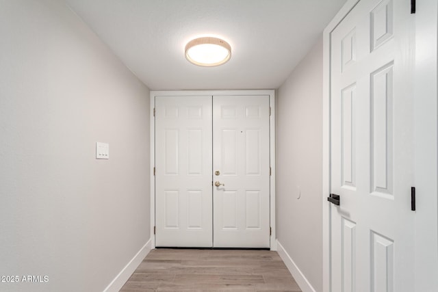 hall featuring light wood-type flooring and baseboards