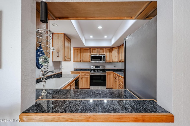 kitchen with tile countertops, recessed lighting, stainless steel appliances, a peninsula, and a sink