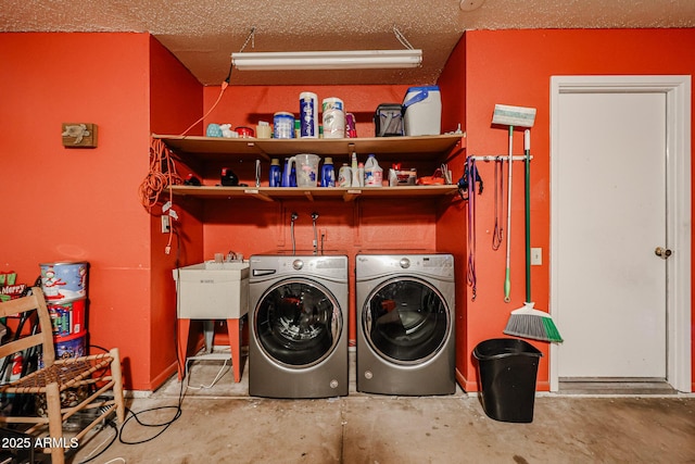 laundry area with laundry area, a textured ceiling, washer and clothes dryer, and a sink