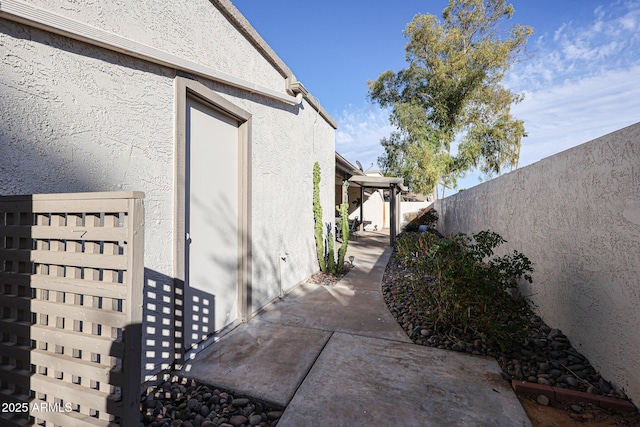 view of property exterior featuring stucco siding, fence, and a patio