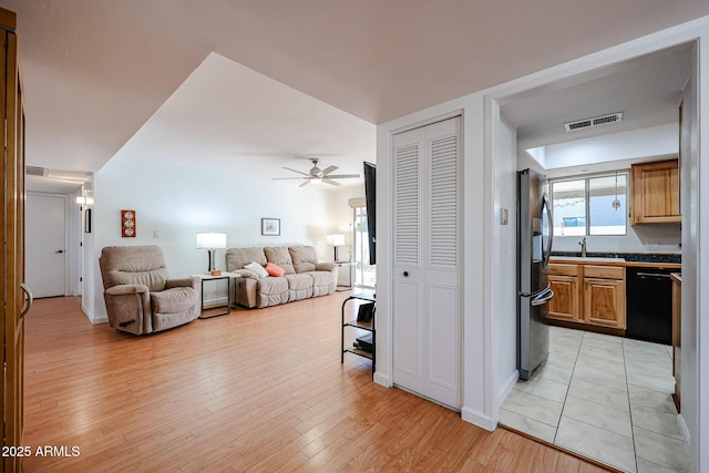 living area featuring light wood-style flooring, visible vents, and ceiling fan