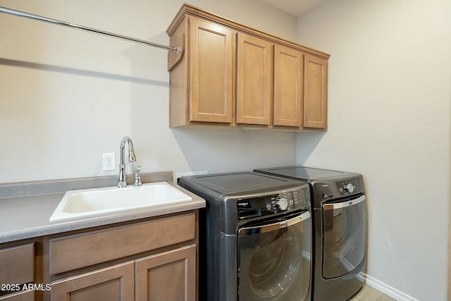 clothes washing area featuring cabinet space, independent washer and dryer, and a sink