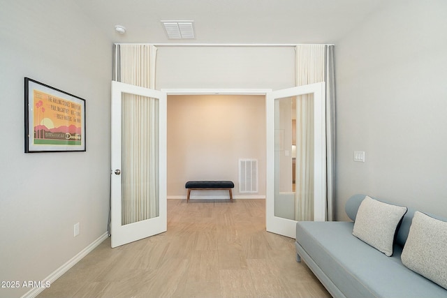 sitting room featuring french doors, baseboards, visible vents, and light wood-style flooring