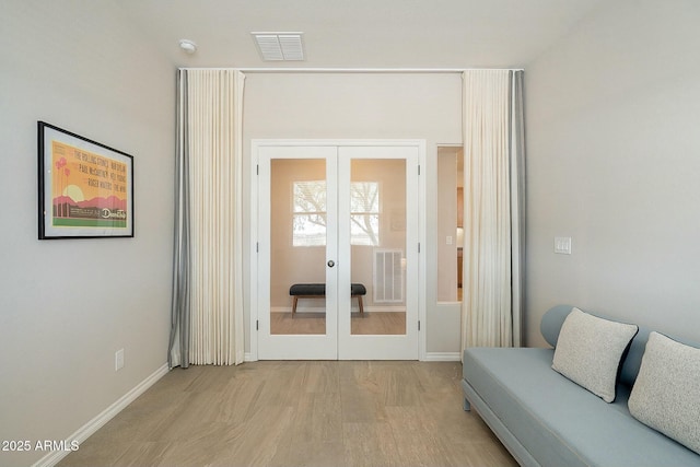 interior space featuring light wood-style flooring, french doors, visible vents, and baseboards