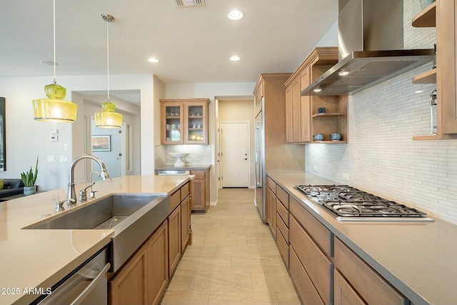 kitchen with a sink, ventilation hood, stainless steel appliances, light countertops, and hanging light fixtures