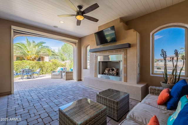 view of patio featuring an outdoor living space with a fireplace, outdoor dining area, and a ceiling fan