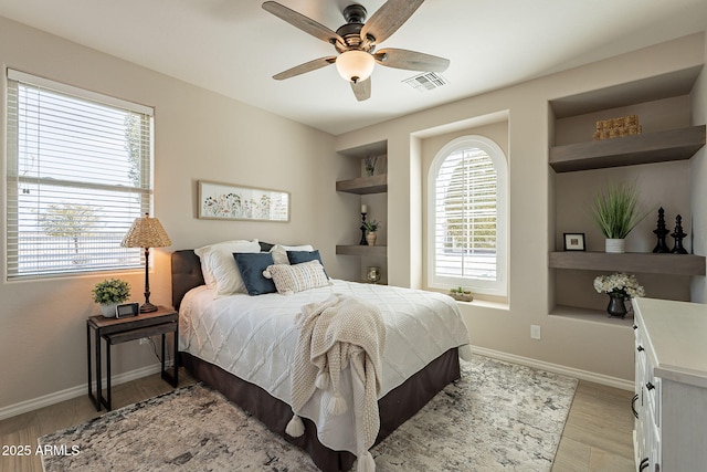 bedroom featuring light wood-style floors, baseboards, visible vents, and ceiling fan