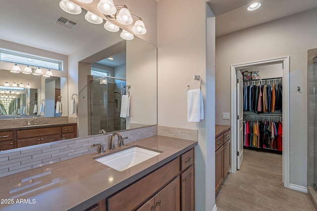 bathroom with decorative backsplash, two vanities, a stall shower, and a sink