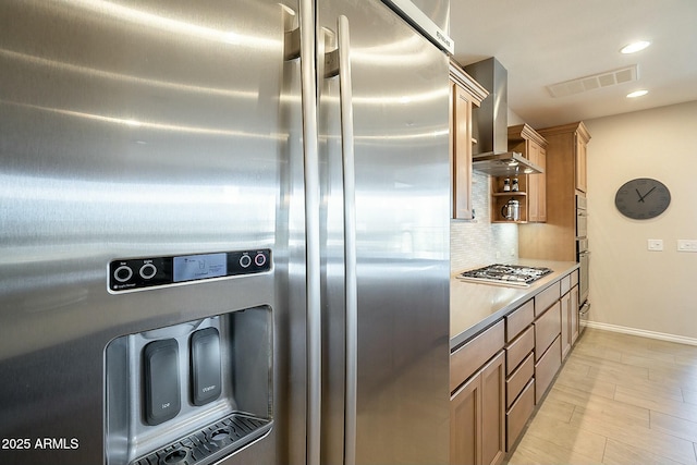 kitchen with visible vents, backsplash, wall chimney range hood, light countertops, and stainless steel appliances