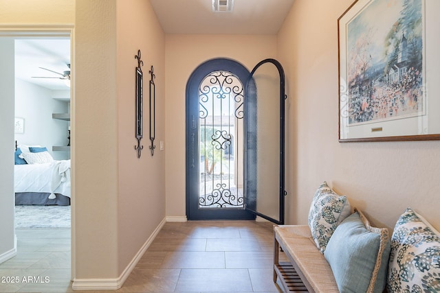 entryway with ceiling fan, visible vents, baseboards, and light tile patterned flooring