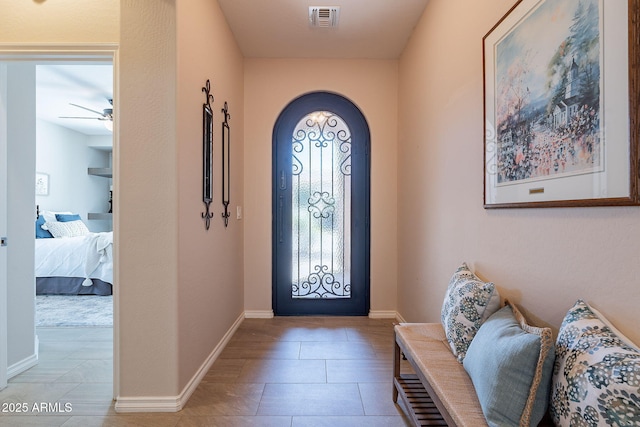 foyer with light tile patterned floors, visible vents, baseboards, arched walkways, and ceiling fan