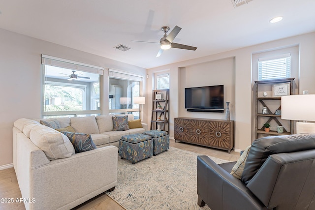 living area with light wood-type flooring, visible vents, baseboards, and ceiling fan