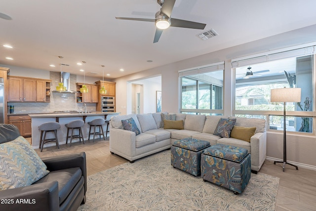 living area with visible vents, light wood-type flooring, a ceiling fan, recessed lighting, and baseboards