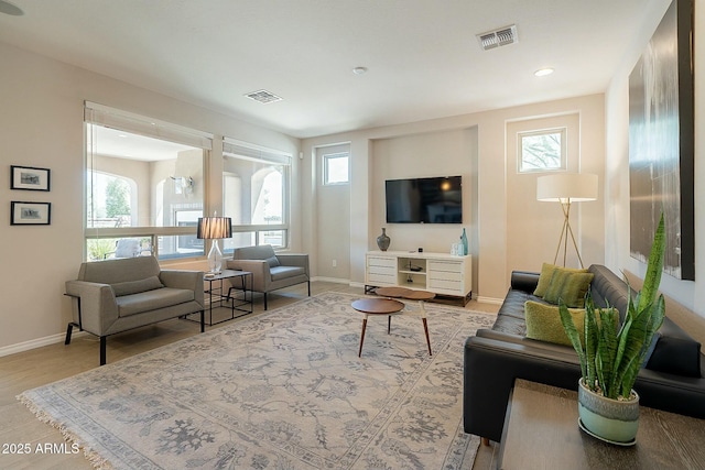 living area with visible vents, plenty of natural light, and wood finished floors