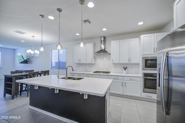 5621 W Chuck Box Rd, Laveen, AZ 85339 - kitchen with appliances with stainless steel finishes, wall chimney range hood, light countertops, white cabinetry, and decorative backsplash