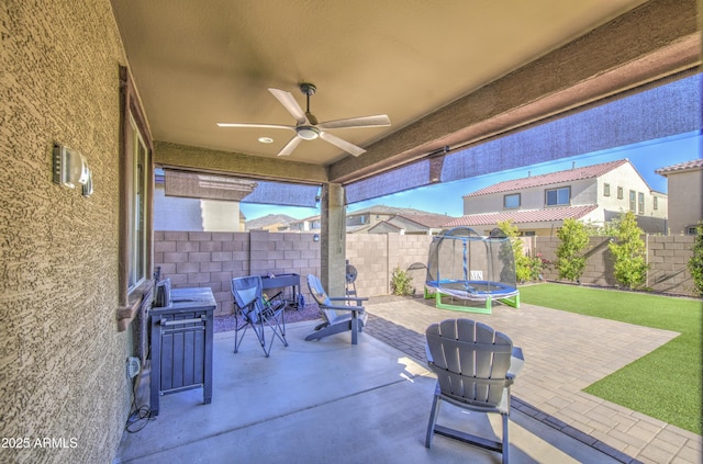 5621 W Chuck Box Rd, Laveen, AZ 85339 - fenced backyard with a trampoline, a ceiling fan, and a patio area