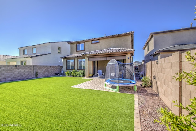 5621 W Chuck Box Rd, Laveen, AZ 85339 - back of property with a trampoline, a fenced backyard, and stucco siding