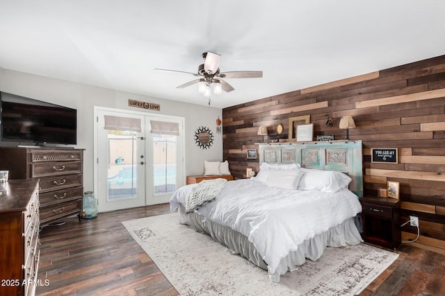 bedroom with wooden walls, access to exterior, dark hardwood / wood-style flooring, and french doors