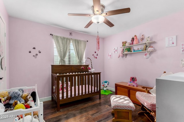 bedroom featuring a crib, dark hardwood / wood-style floors, and ceiling fan