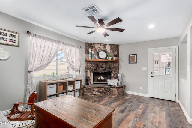 living room featuring a stone fireplace, hardwood / wood-style floors, and ceiling fan