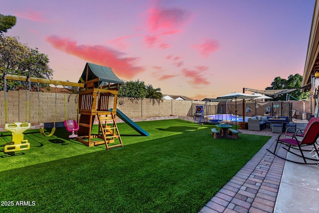 yard at dusk featuring an outdoor hangout area, a playground, and a patio area