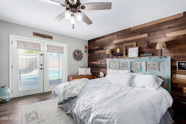 bedroom featuring french doors, wood walls, dark wood-type flooring, and access to outside