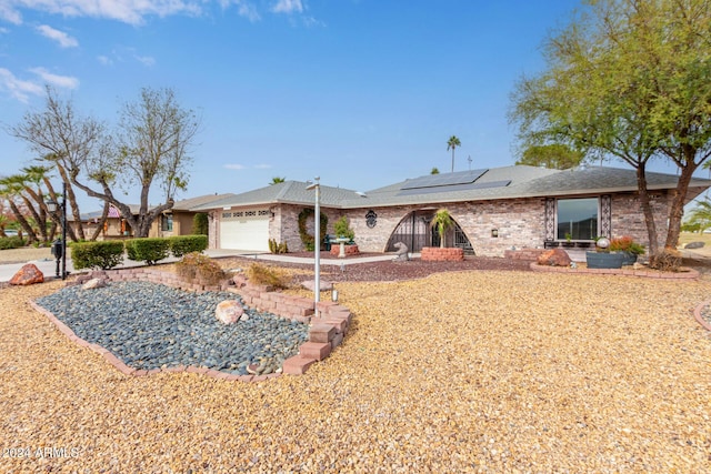 view of front of property featuring solar panels and a garage