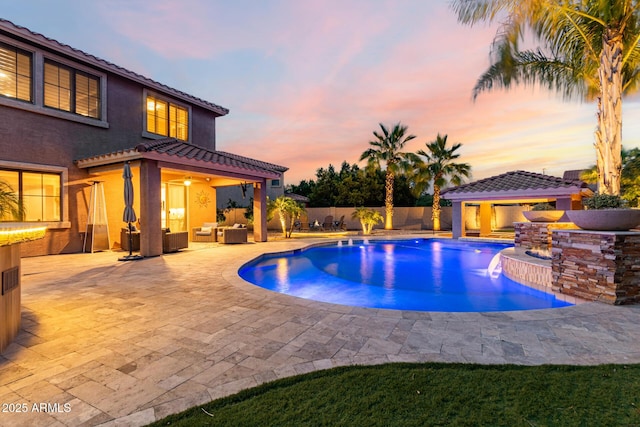1179 E Regent Dr, Gilbert, AZ 85298 - pool at dusk featuring outdoor lounge area, a fenced backyard, a patio, and a gazebo