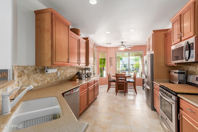 kitchen featuring decorative backsplash, sink, light tile patterned floors, appliances with stainless steel finishes, and ceiling fan