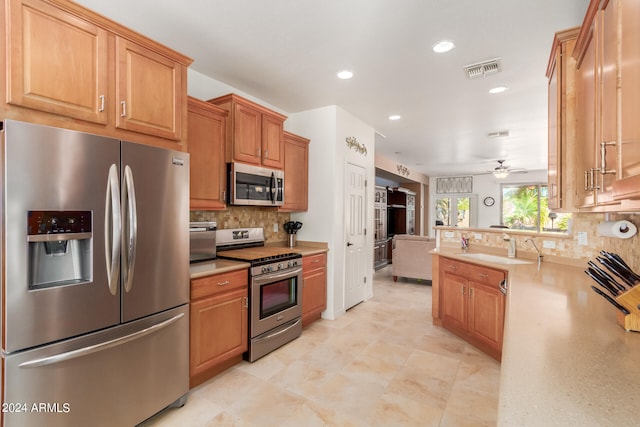 kitchen featuring ceiling fan, appliances with stainless steel finishes, sink, and decorative backsplash