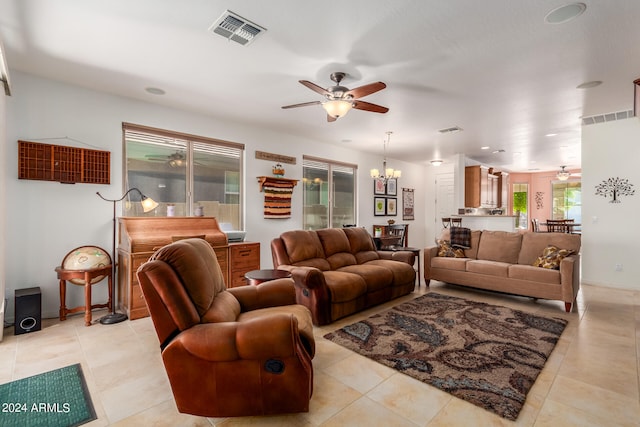 tiled living room with ceiling fan with notable chandelier