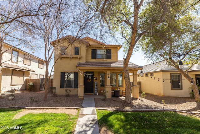 view of front of property featuring covered porch, a tiled roof, fence, and stucco siding