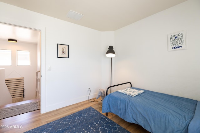 bedroom with wood finished floors, visible vents, and baseboards