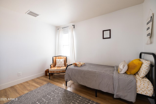 bedroom featuring visible vents, baseboards, and wood finished floors