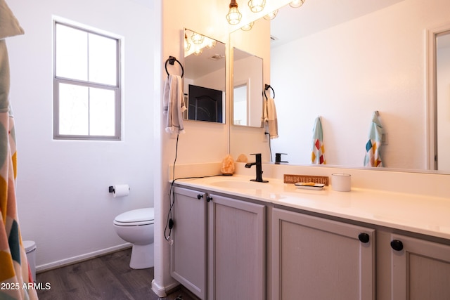 bathroom with wood finished floors, vanity, toilet, and baseboards