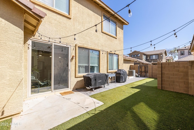 back of house with stucco siding, a yard, fence, and a patio