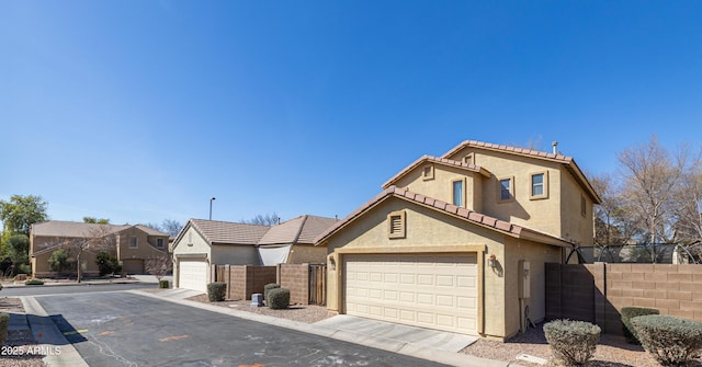 view of front of house with a garage, driveway, fence, and stucco siding