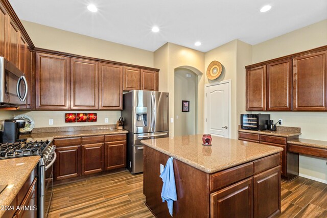 kitchen featuring light stone counters, dark wood-type flooring, a kitchen island, and stainless steel appliances